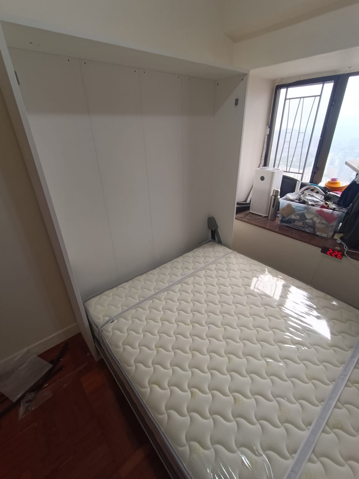 睡房實景中，白色高身直翻床箱靠牆並在窗台旁打開，白色波浪紋床褥以兩條固定帶扣好，床架延伸至木地板上。
