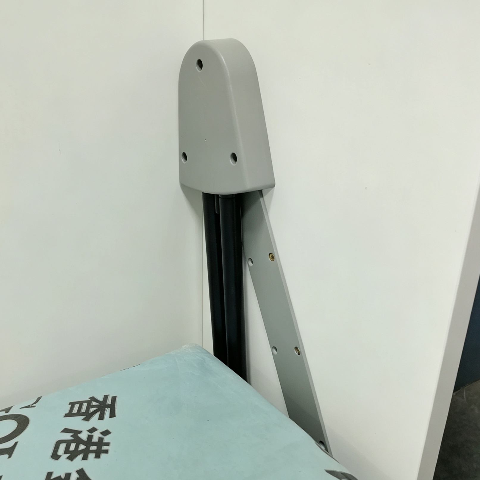白色直翻床箱內側的開合結構近鏡，灰色圓角護蓋包住黑色直軌上端，斜向灰色金屬支架位於淺藍色床褥旁，清楚可見。