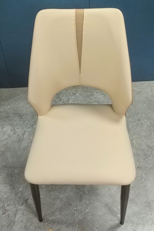 餐椅正面實拍，米色仿皮高背中央加入淺啡直向縫線，腰位設弧形開孔，寬闊米色座面下配四隻深灰色錐形金屬腳。
