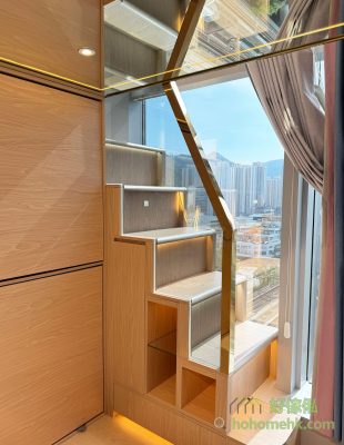 The staircase cabinets have grey glass with a gold stainless steel border that complements the light wood color while keeping light in the lower loft.