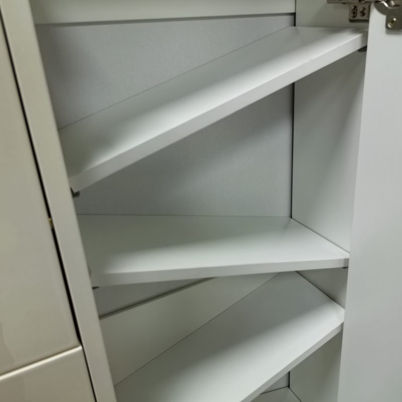 Caleb鞋櫃內部工廠實拍，翻斗門開起狀態下露出上、中、下三層淨白斜面隔板，右邊可見金屬鉸鏈連拉柄底座，整體以淺灰白色調為主。