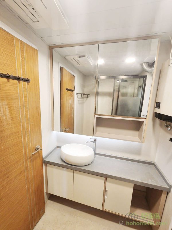 廚櫃、浴室櫃及客廳、睡房的訂造傢俬均採用相同的材質及設計風格，令整個單位的視覺效果顯得更為統一。無論是廚房的潔白牆身，還是浴室的簡約線條，每一件訂造傢俬都體現了細緻的工藝。開放式廚房選擇灰杏色和大面積的奶油色，使整個客廳空間顯得更寬敞光亮。