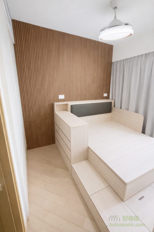 今次的睡房傢俬案例的主角一定是胡桃木色的條子背景牆，牆身以胡桃木色條子飾面覆蓋，令原本單調的牆壁瞬間變得有層次感和高級感。木紋的自然紋理和柔和色調，為空間注入溫暖氛圍，同時展現出一種低調奢華的設計美學。