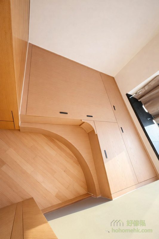 房訂造的全新地台與客戶原有的衣櫃採用了統一的全木色設計，令整體空間顯得簡潔有序。地台附設的1/4圓形梯級設計，既方便登上地台，又增添了視覺上的趣味性，為空間注入一絲柔和的動感。