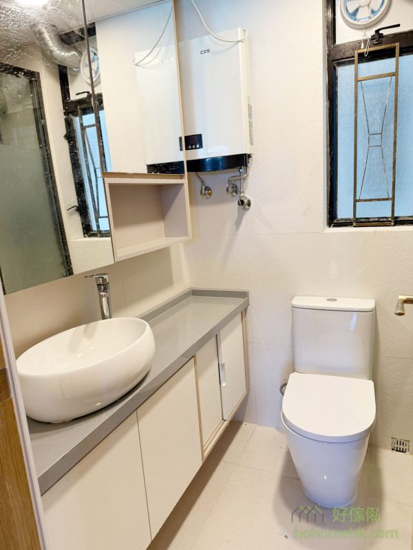 廚櫃、浴室櫃及客廳、睡房的訂造傢俬均採用相同的材質及設計風格，令整個單位的視覺效果顯得更為統一。無論是廚房的潔白牆身，還是浴室的簡約線條，每一件訂造傢俬都體現了細緻的工藝。開放式廚房選擇灰杏色和大面積的奶油色，使整個客廳空間顯得更寬敞光亮。