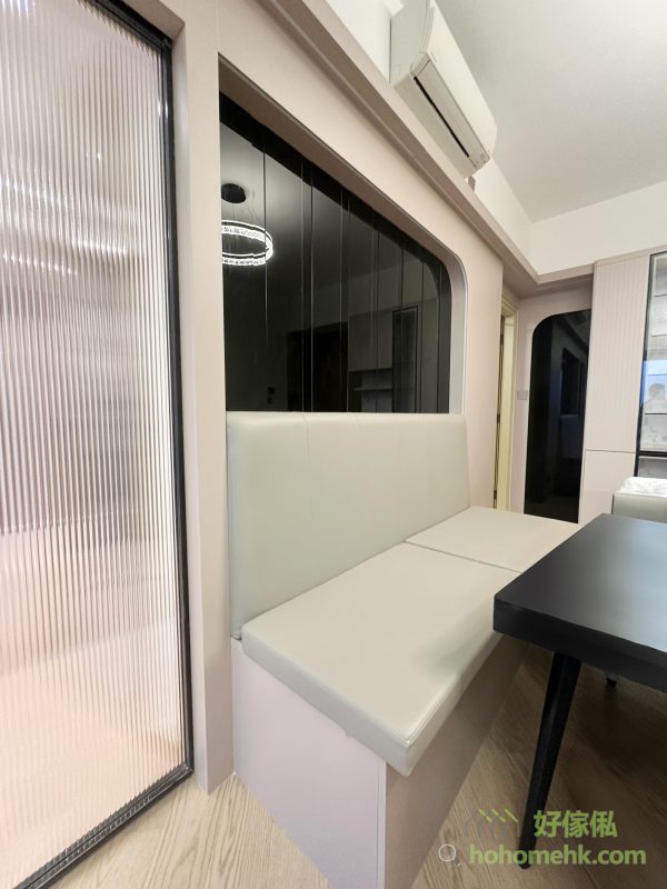 電視背景牆自然延伸至飯廳，與卡座背景牆無縫過渡，形成連貫的設計效果。卡座的靠背與座位均加入cushion設計，提升舒適度，同時有效利用空間，揭開卡座亦是很大的儲物空間。旁邊的黑玻璃設計，進一步增加飯廳的空間感與格調。