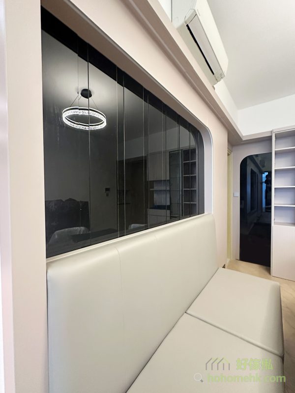 電視背景牆自然延伸至飯廳，與卡座背景牆無縫過渡，形成連貫的設計效果。卡座的靠背與座位均加入cushion設計，提升舒適度，同時有效利用空間，揭開卡座亦是很大的儲物空間。旁邊的黑玻璃設計，進一步增加飯廳的空間感與格調。