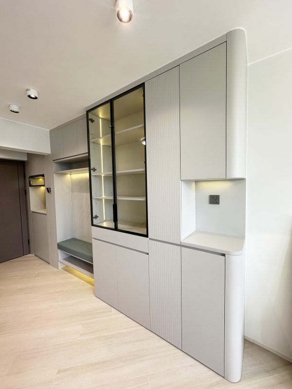 一進門口，映入眼簾的是一組精心設計的多功能組合櫃。設計包括C字櫃、飾物玻璃櫃、洞洞板掛衣區和換鞋凳，以及下方的儲物區，使每一部分都物盡其用。特別是坐墊下方的儲物空間，方便放置常用的鞋履，背後的洞洞板亦可輕鬆吸附磁石，功能多樣又貼心。