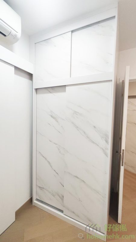 房內的衣櫃亦沿用電視櫃及背景牆的板材及紋理，確保全屋設計風格一致。大理石紋的衣櫃簡約時尚，實用之餘更顯生活品味。這種設計不僅耐看，亦符合現代人對簡約生活的追求。