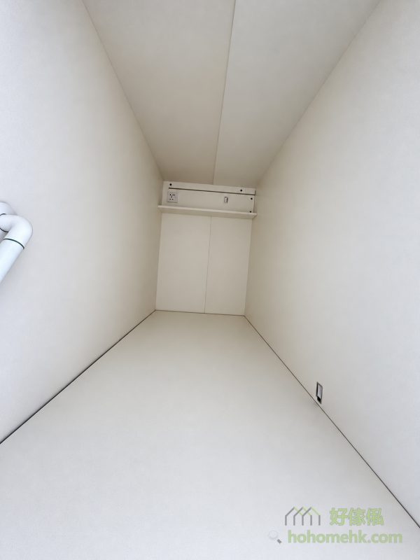 由床尾望入白色工人床櫃內籠，可見平整床台及兩側淺色牆板，床頭上方裝有窄層板、插座與掣位，左側牆身另設彎曲白色扶手。